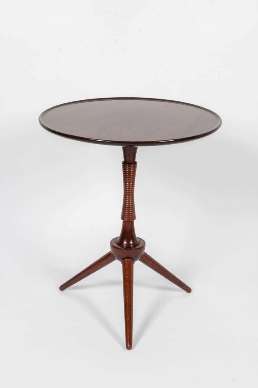 A Danish mahogany side table, Circa 1940s, the circular top with a lipped outer edge raised on an interesting waisted turned stem and ending with a tripod base.
