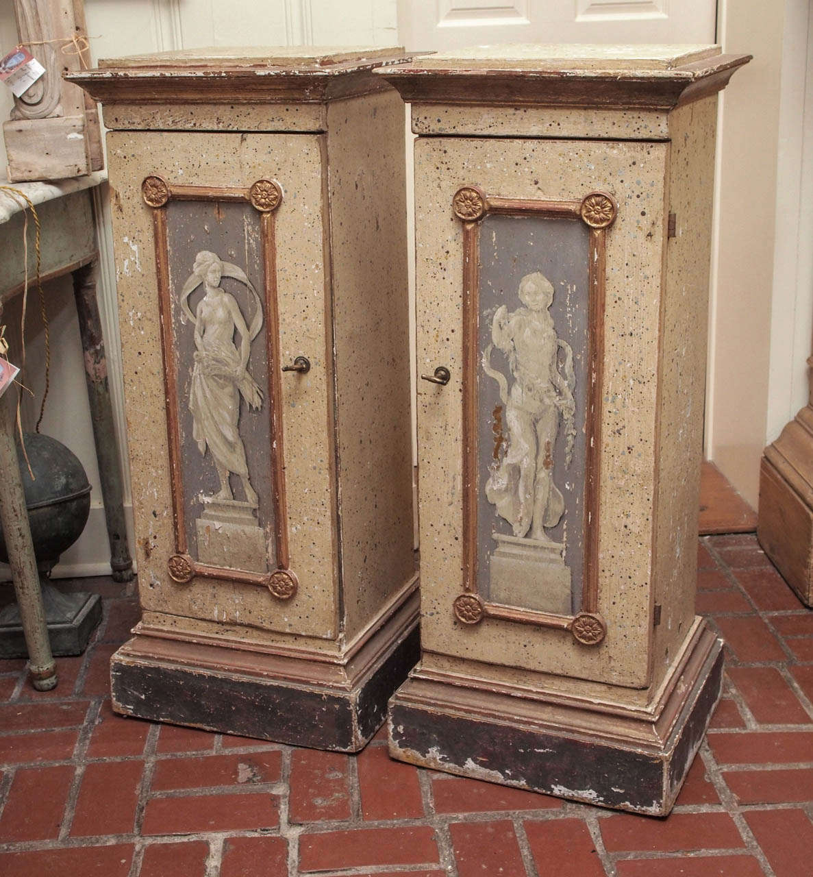 A pair of 19th century Italian painted plinths with faux bas relief motifs and giltwood accents. They are actually cabinets with one interior shelf. Original hardware and keys.