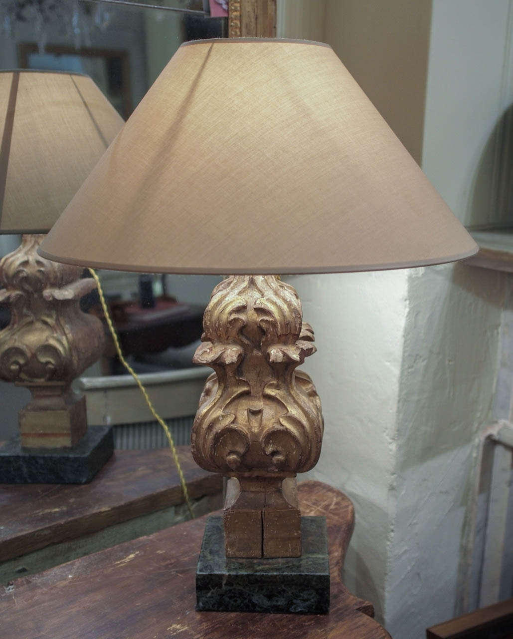 A pair of carved gilt wood architectural fragments made into lamps mounted on green marble base with shades