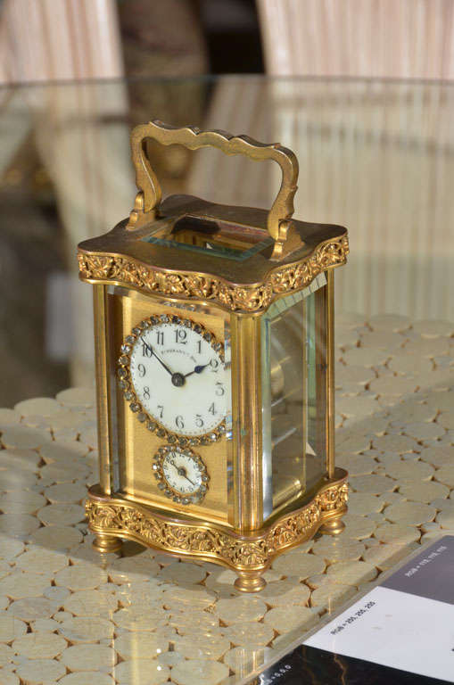 Beautiful gilted brass carriage clock, with filigree base and top. Rhinestone bezels around face and alarm. In good working order.Alarm works.