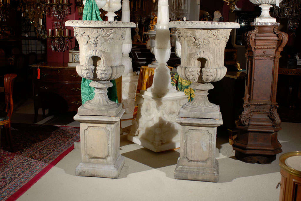 Fantastic pair of cast stone urns raised on pedestals, the overall height of the urn with pedestal is 62.5 inches. 