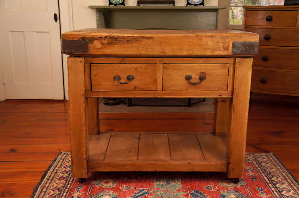 This husky authentic old butcher block from and English meat cutter shop has found a home on a reproduction base.It is the jperfect marriage of old and new. The top has metal straps on all four corners. the base has been stained to match the top