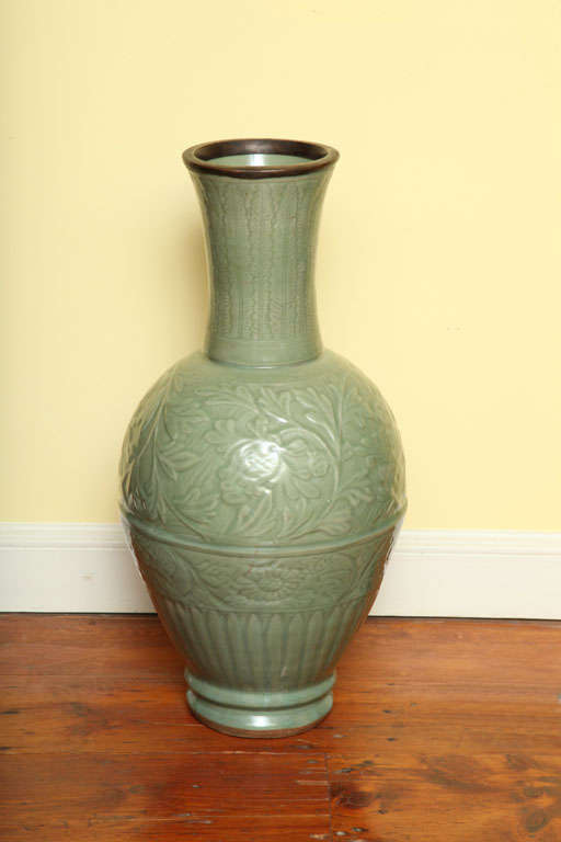 Large antique Yuan Dynasty celadon jar decorated with raisedleaf pattern in the neck above two registers of swirling floral and leaf patterns above leaf fluting.  14th century