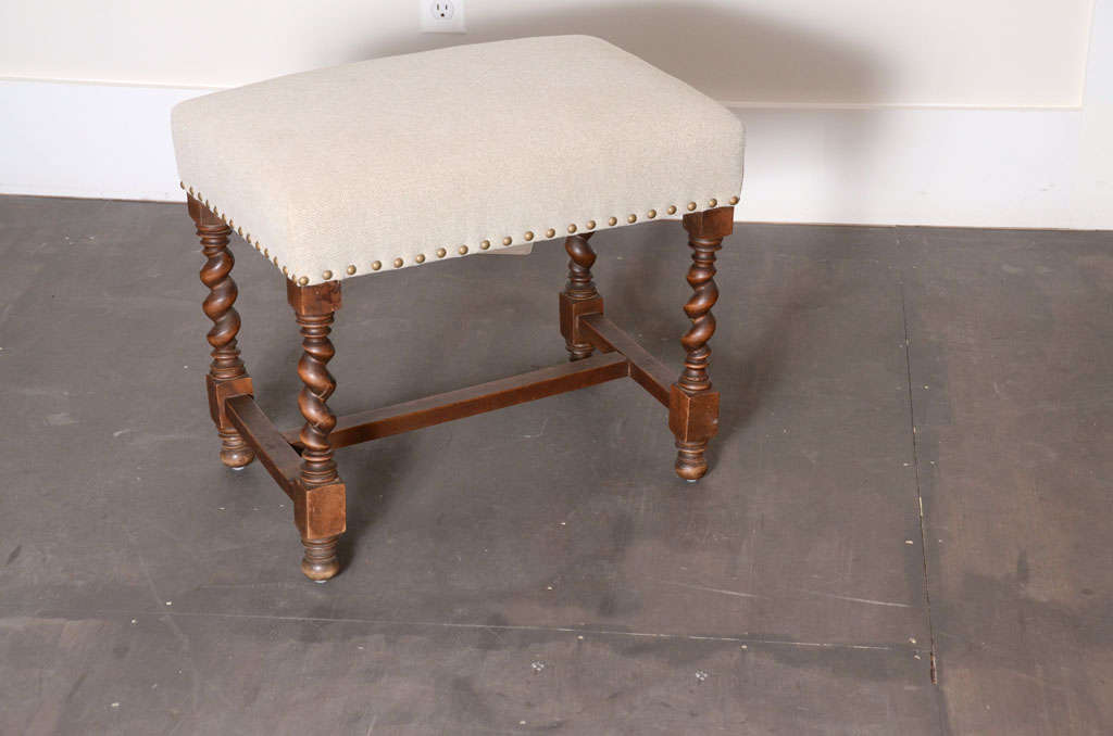 Antique barley twisted foot stool, France, early 20th century. 

Delightful design consists of barley twist legs, peg feet, and new upholstery in a cream linen with brass nail heads. 
 