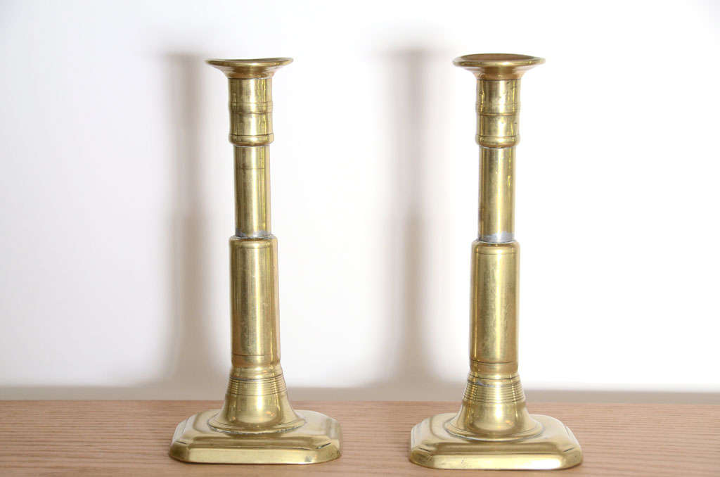 Pair of Polished Brass Candlesticks with Rectangular Bases, England, c. 19th Century. 

These candlesticks bear the modest elegance and storied beauty of late 19th century England. Wonderful decorative accessories, the pair adds a healthy layer of