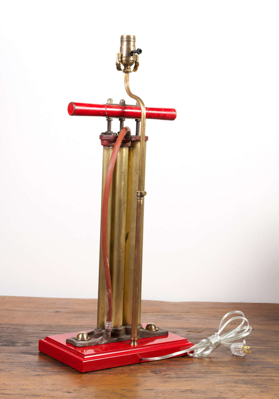 Lovely vintage bike pump newly wired as table lamp.  Candy red base compliments the raw brass pump with red detail.