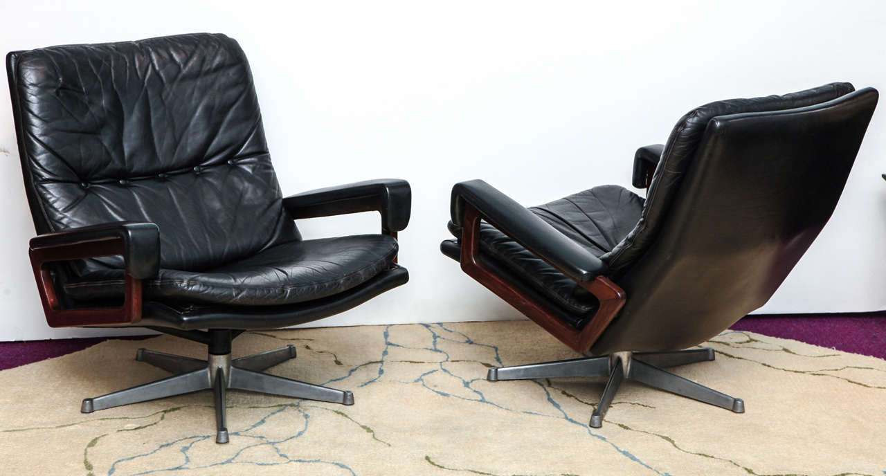 Elegant pair of chairs with original leather upholstery and mahogany arms on steel swivel bases.  These chairs are incredibly comfortable with a lot of style.
