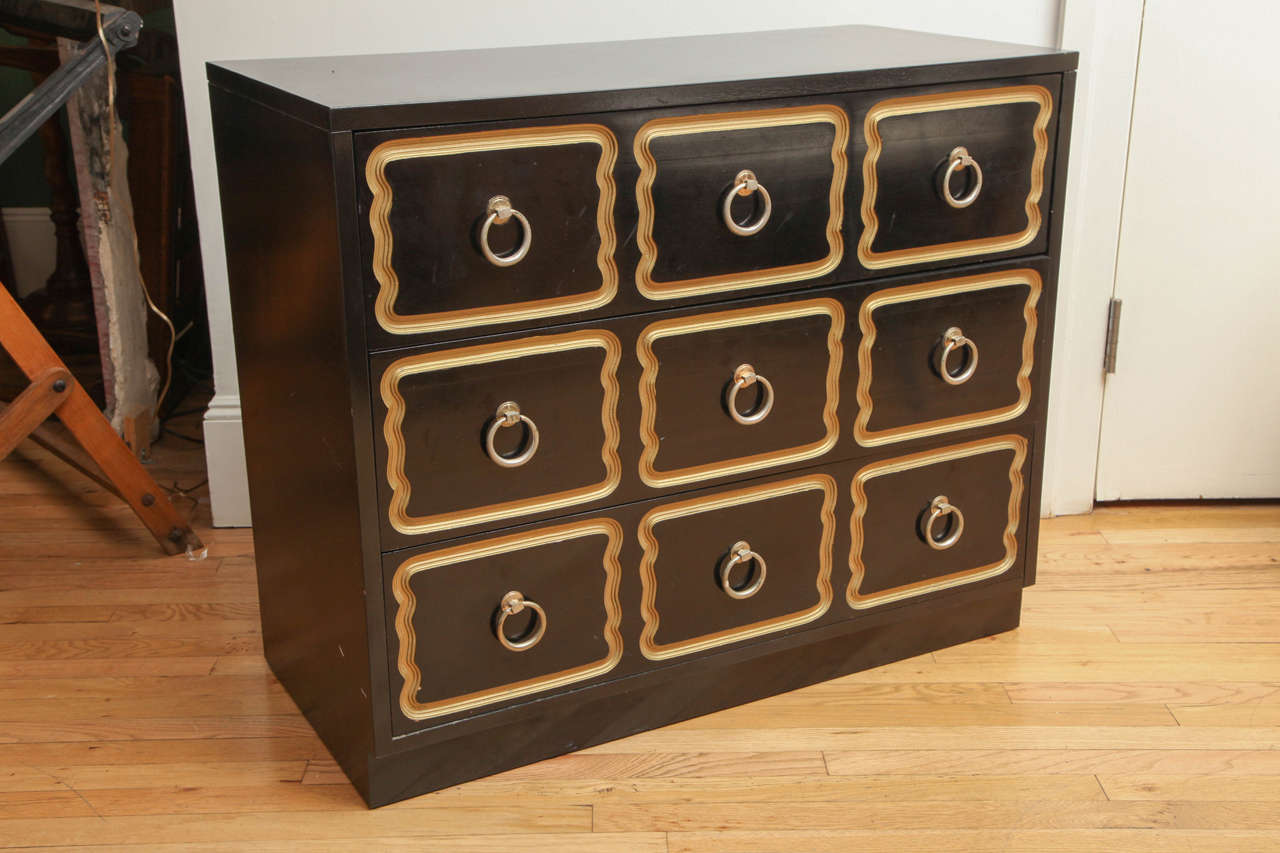 Rectangular chest with black lacquer finish, features three drawers decorated with a repeated routed pattern. Solid brass ring pulls adorn the centers of the nine shapes.