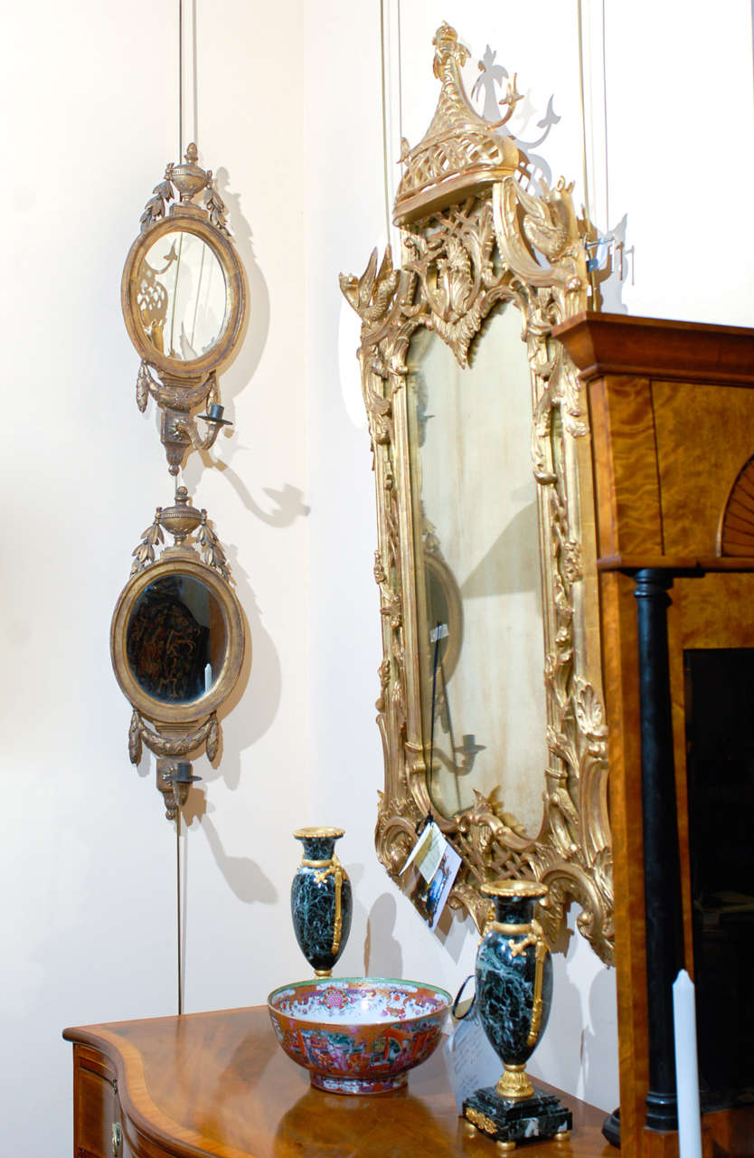 A Louis XVI style gilt-wood oval mirrors with single arm sconces,  urn and garland motifs. 

William Word Fine Antiques: Atlanta's source for antique interiors since 1956. 

