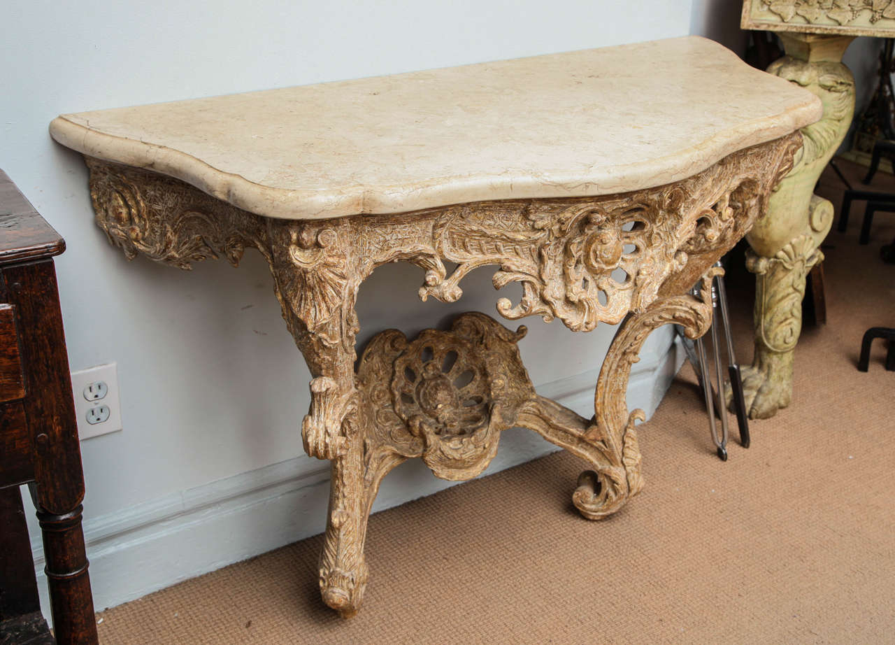 Very fine 18th century Rococo carved and giltwood console table with lobed shell and foliate carving in lovely old surface stripped down to the original gilding, having crisp carving and very fluid design, the later shaped marble top over scroll and