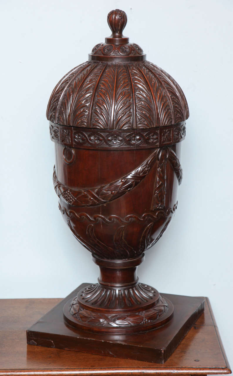 English mahogany wine cistern of impressive scale, the acanthus carved lid with bursting pomegranate finial, over urn shaped body with wreath and garland carving over wave scrolling, over curved long leaf decoration, the fluted and and wreath carved