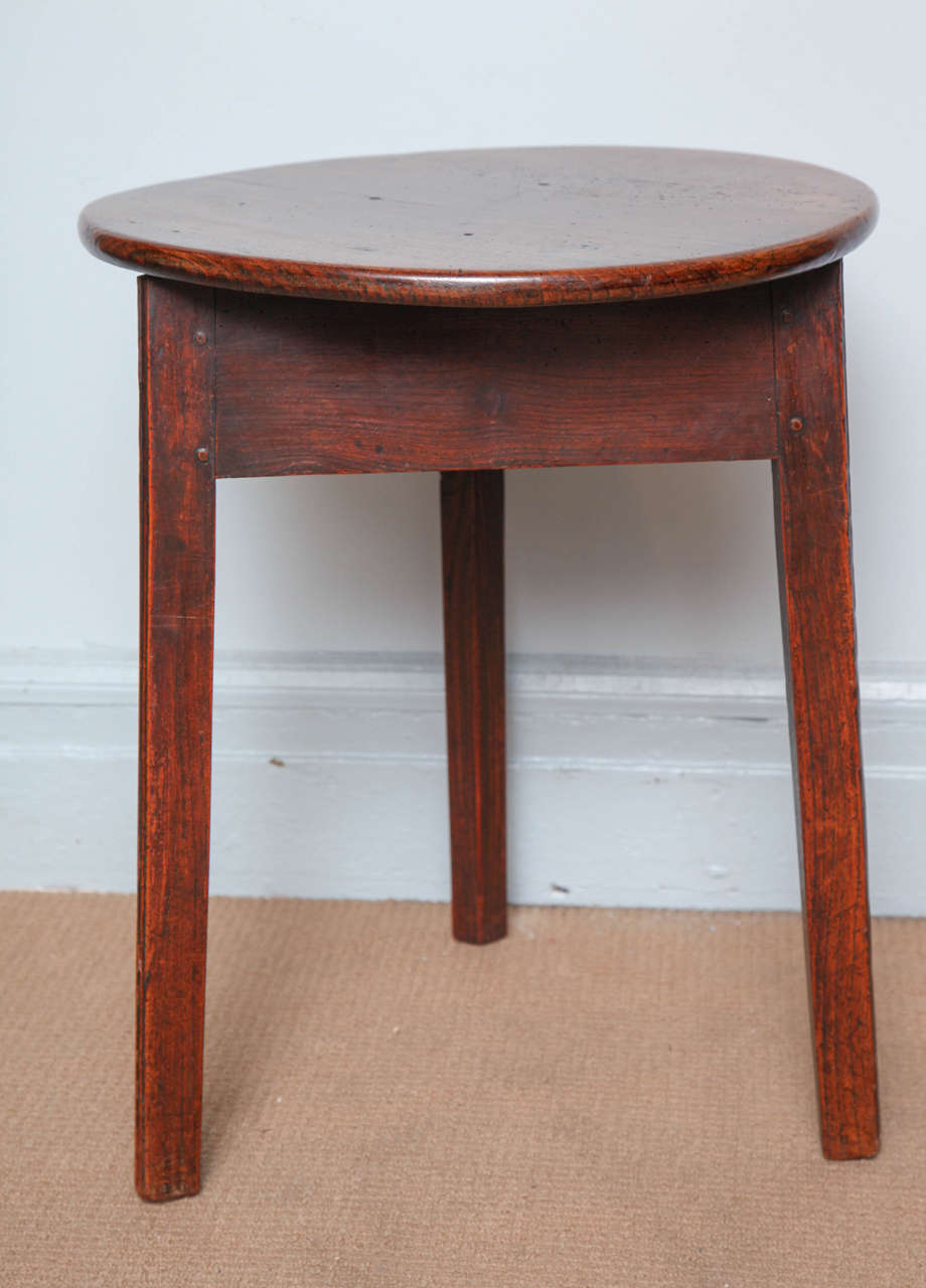 Unusually diminutive English or Welsh cricket table, the single elm plank top having numerous scars and burns and possessing a good rich patina, over triangular apron above three slightly spayed legs, again all having good rich color.