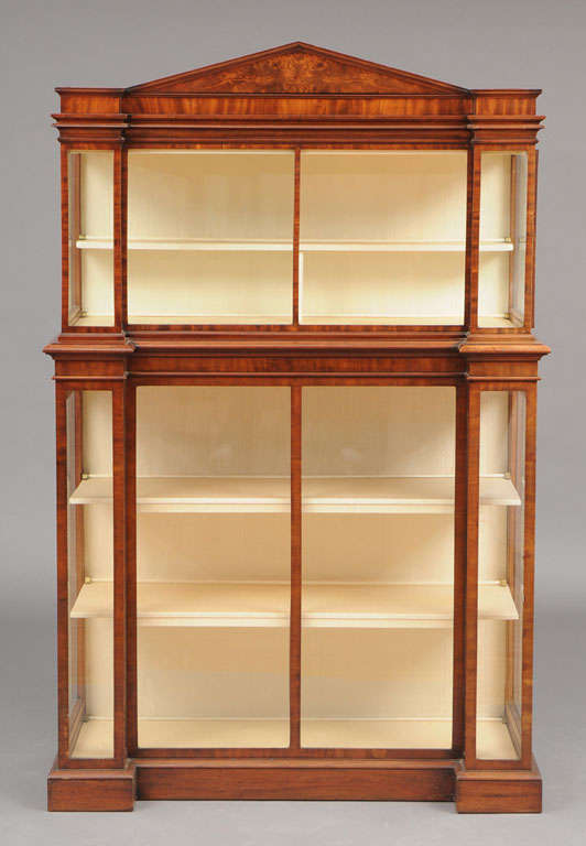 ENGLISH MAHOGANY THREE-PIECE VITRINE CABINET 
Of reverse breakfront outline, the pitched pediment above the set-back upper section with a glazed door at either side, the lower part also with lateral doors enclosing three shelves. Provenance: