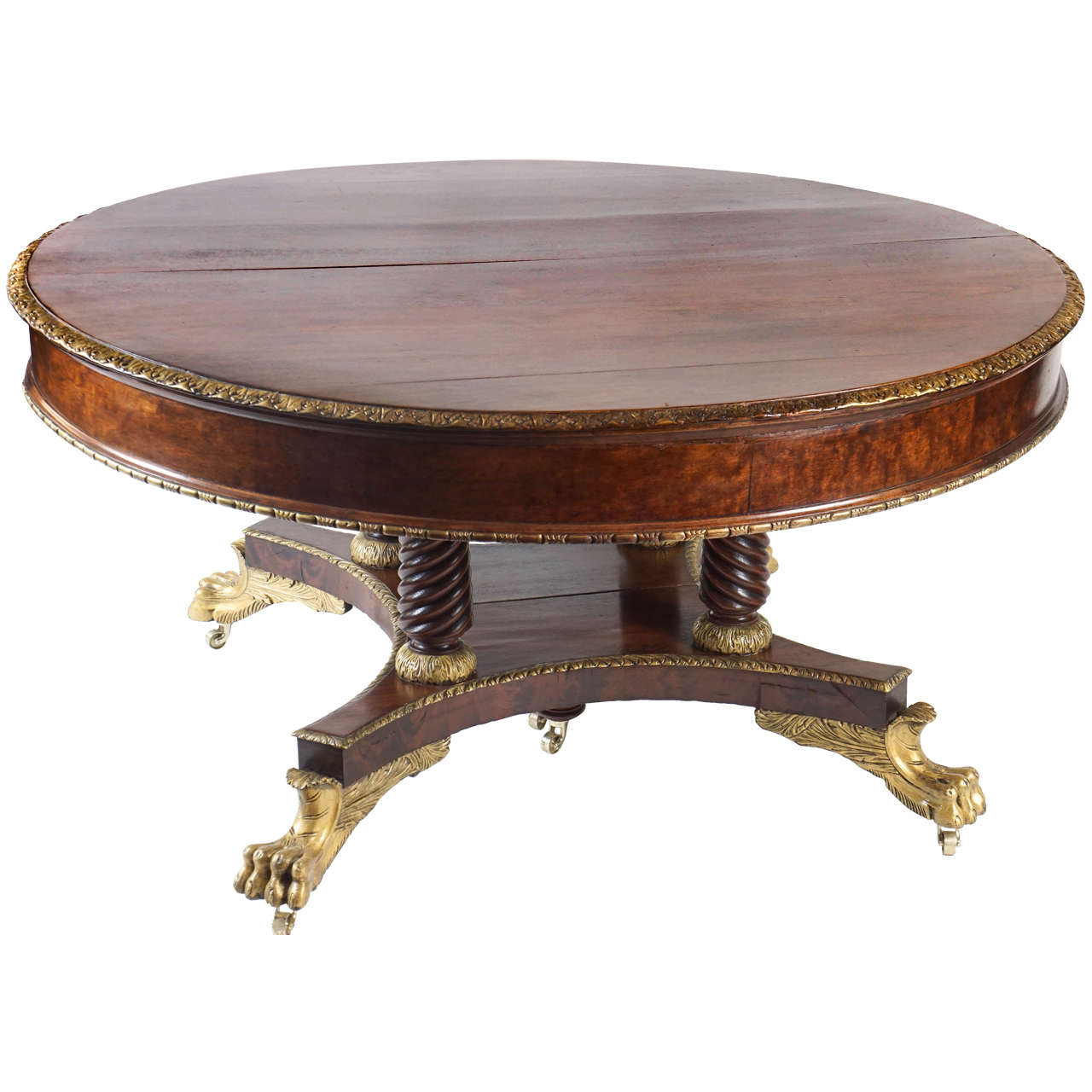 Rare circa 1880 Duncan Phyfe influenced parcel-gilt mahogany extendable dining table attributed to the New York City firm of cabinetmakers Meier and Hagen having round top with carved acanthus gilt top edge and gilt bead-and-reel at bottom apron