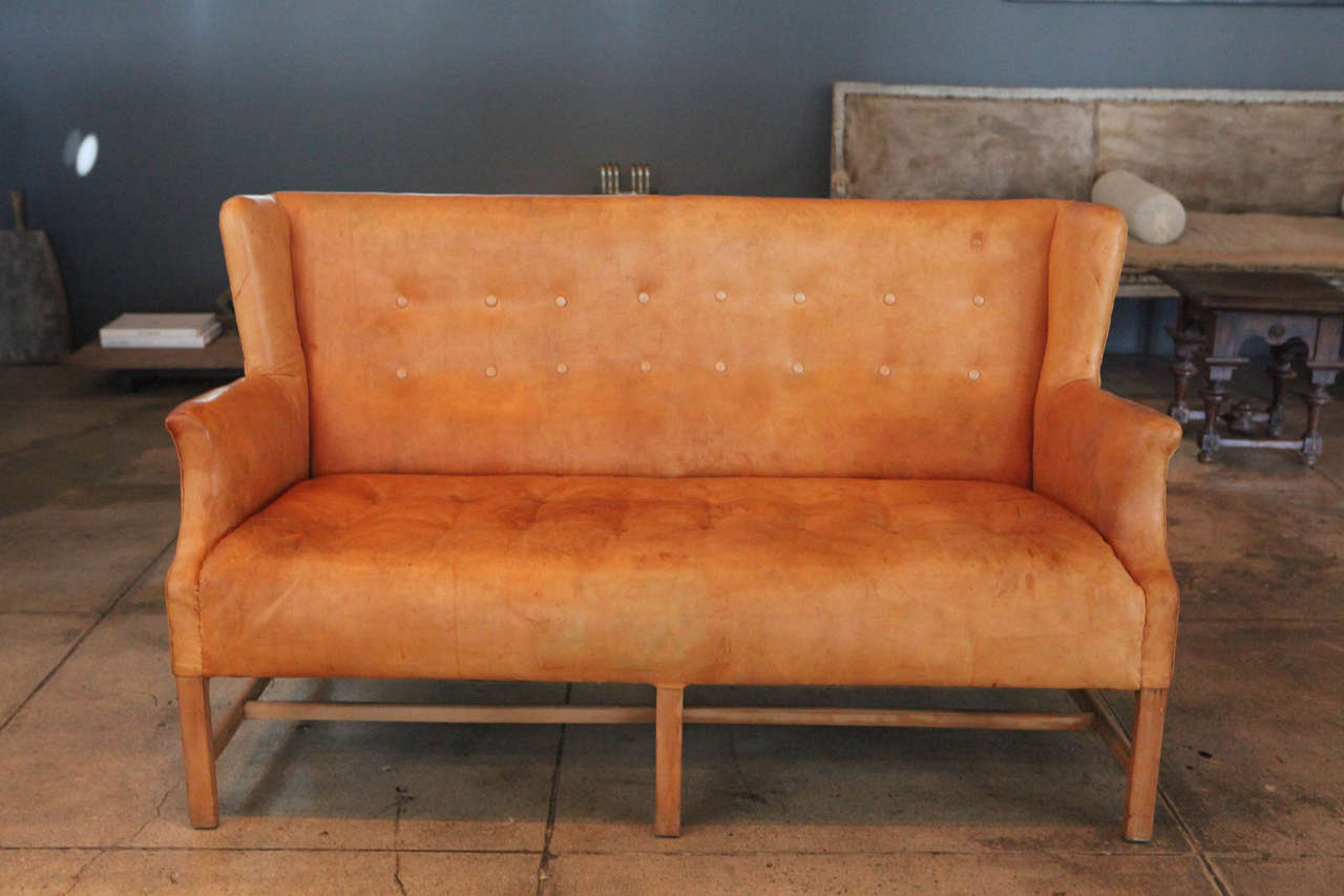 A custom loveseat designed and produced by Rud Rasmussen with its original cognac leather and Cuban mahogany frame.