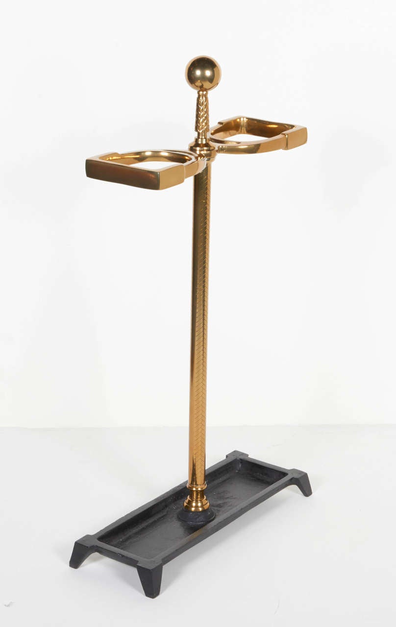 Elegant umbrella stand with equestrian inspired design, featuring stylized horse bit and handle components. The umbrella stand has hand-forged designs with hand incised details along the stem and has a brass ball center handle. Brass-plated steel