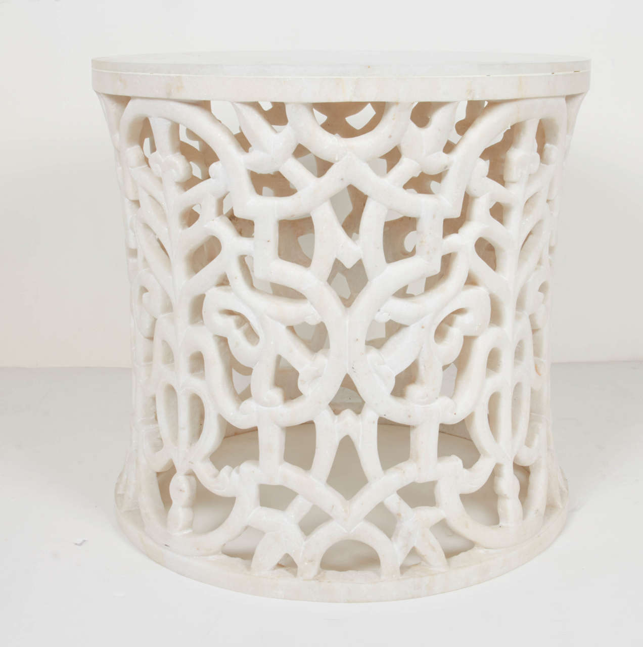 Incredible hand-carved pedestal table or side table in honed white marble. Base has been sculpted from a single piece of marble and features hand-carved Jali designs inspired by Middle Eastern and Indian architecture and window lattices. The table