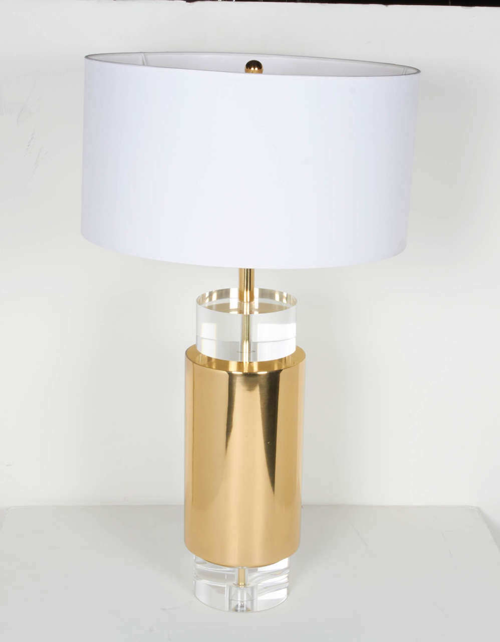 Pair of modernist lamps with cylindrical forms. Comprised of satin brass column centers with stacked circular Lucite top and base. Uber chic design featuring white silk drum shades and brass fittings.