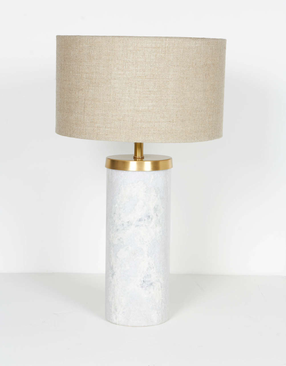 Elegant pair of solid marble table lamps or desk lamps. The lamps have a modern streamline cylinder form with a polished finish and with satin brass fittings. Shown with small woven linen drum shades. The lamps are petite in scale, but heavy in