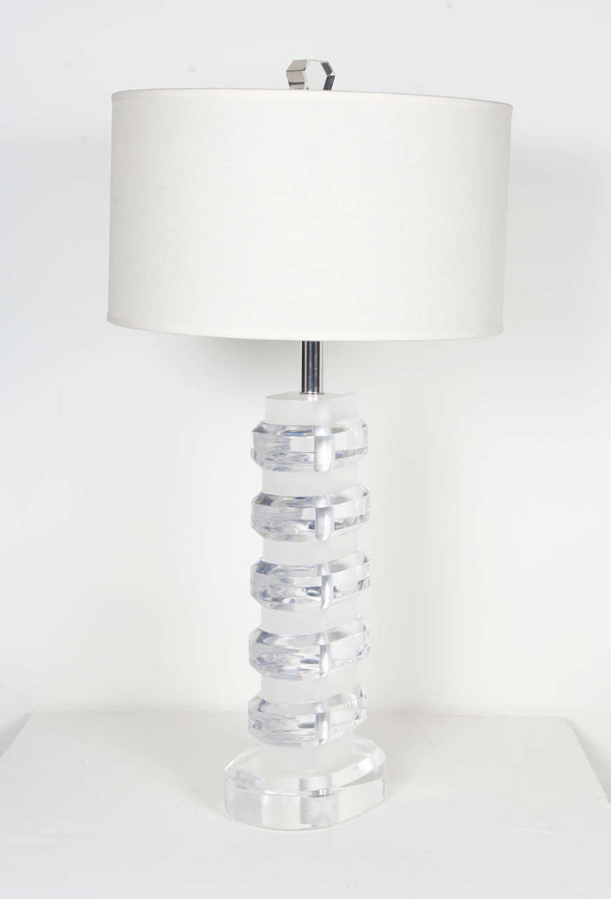 Mid-Century Modern solid Lucite lamp. Comprised of stacked clear and frosted acrylic blocks with stylized oval forms. The Lucite elements have beveled border details and the lamp features a polished chrome stem and fittings. Shown with custom linen