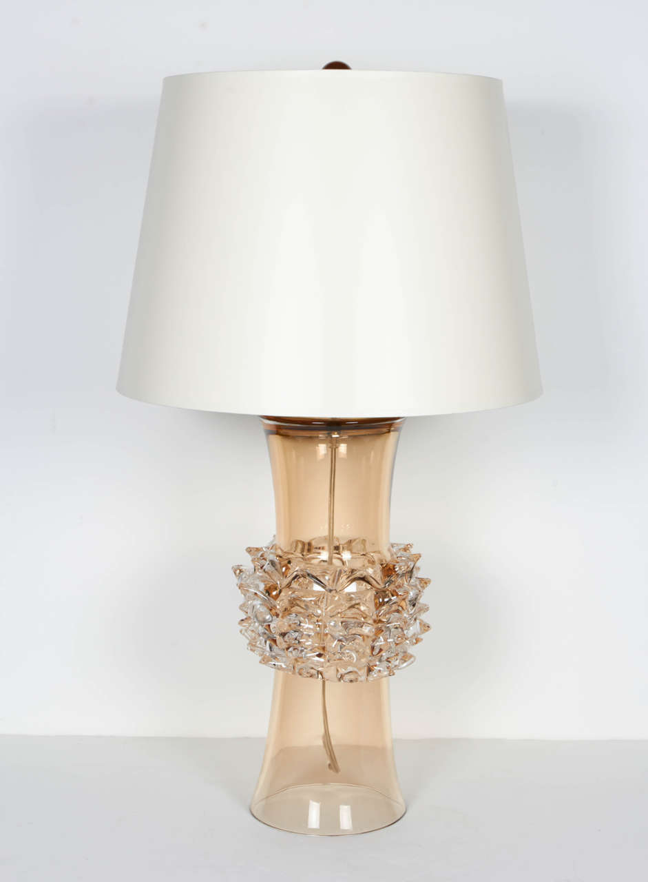 Exquisite pair of handblown and handcrafted amber tinted Murano glass lamps. The lamps have modern hourglass forms and feature 'restrato' technique or spiked glass banded center design. Includes custom matte shades with ivory finish exterior and