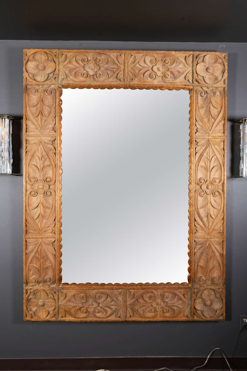 Exquisite vintage Indonesian artisan mirror is hand-carved from reclaimed and washed solid teakwood. The mirror features lotus flowers and other handcrafted floral depictions. Interior scalloped borders feature antiqued gold leaf finish. Glass has