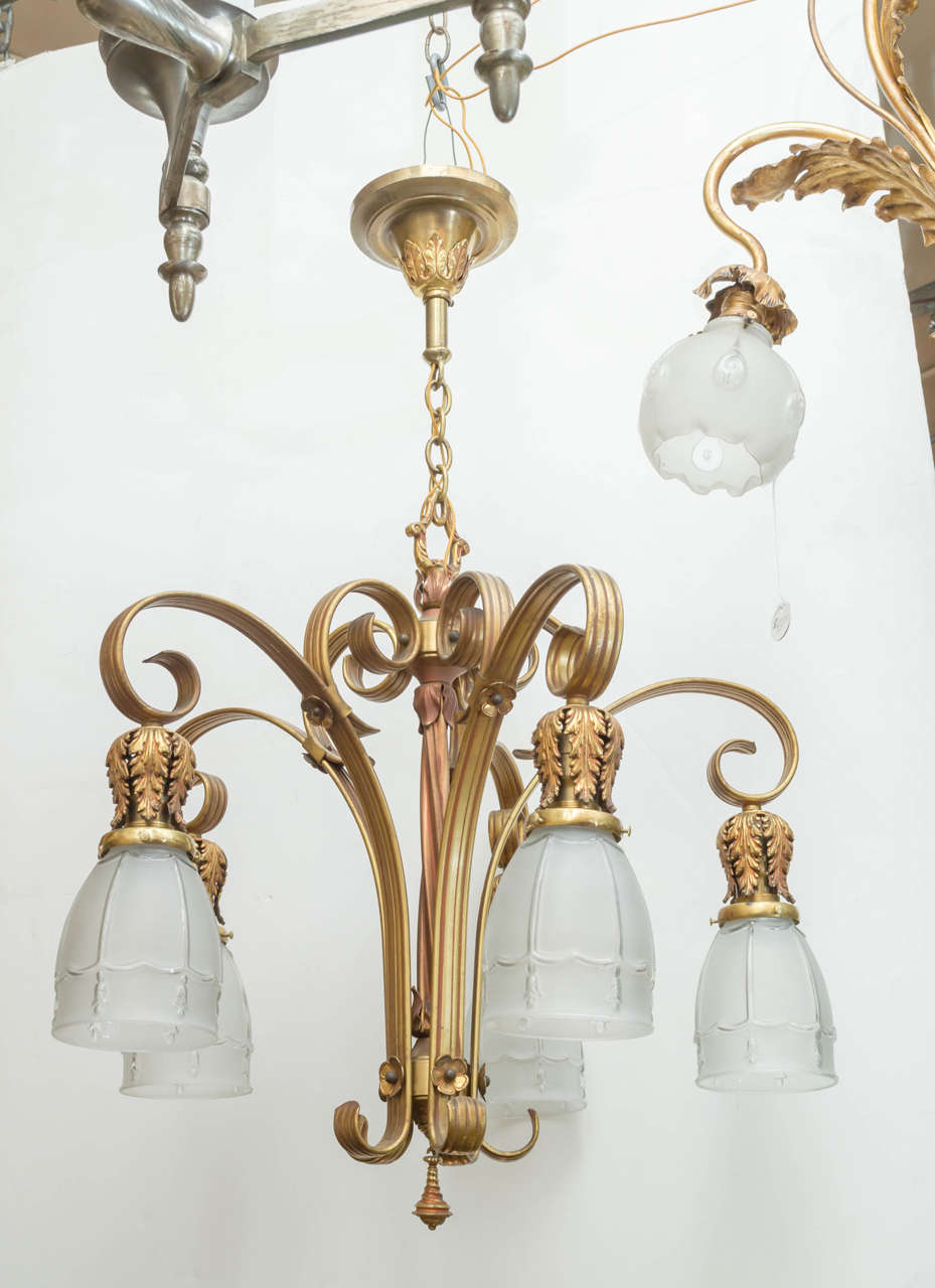 We sell many chandeliers,but this one is admittedly quite unusual. It has a luscious gilt finish, and the center has an unusual twisted metal design. We put those shades on the chandelier,as it came to us without glass. The shades are period to the