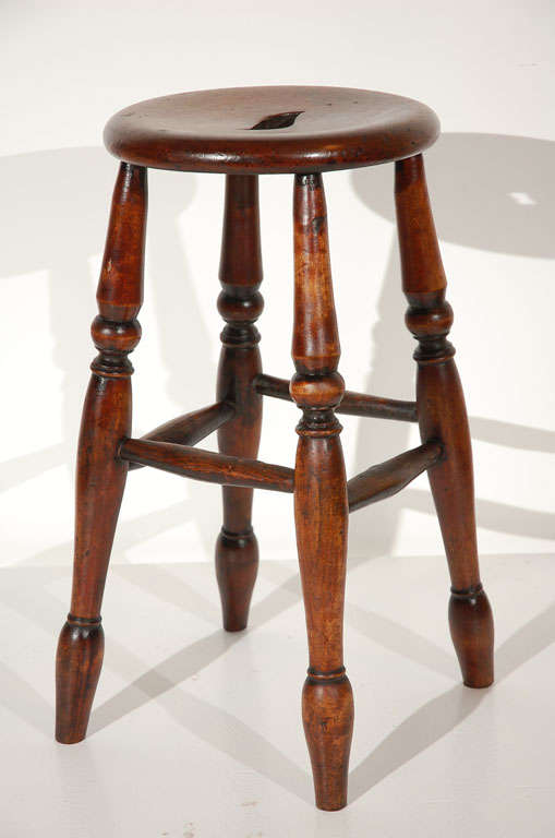 Early and wonderful form 18th century stool from New England in old red stain finish. This stool has the most wonderful patina of any stool I have ever seen. The turnings are done by hand and have the most beautiful surface. This is in good