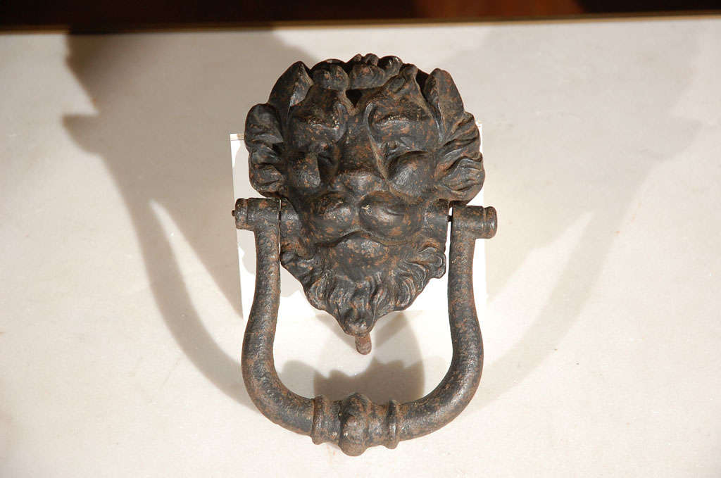 Antique cast iron doorknocker with a lion's face. Great character and strength to the lion face and natural patina throughout with old black paint. Bolts add 2 3/3