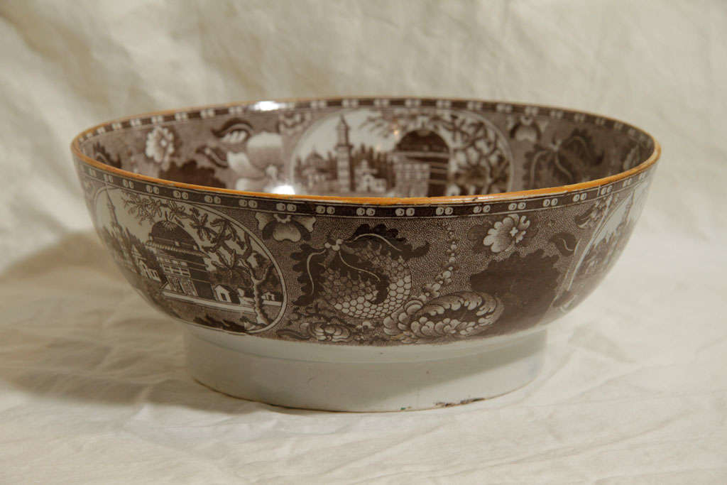 A Pearlware punch bowl with brown transferware showing typical Staffordshire imagery of flowers, village scenes and a sailing ship.