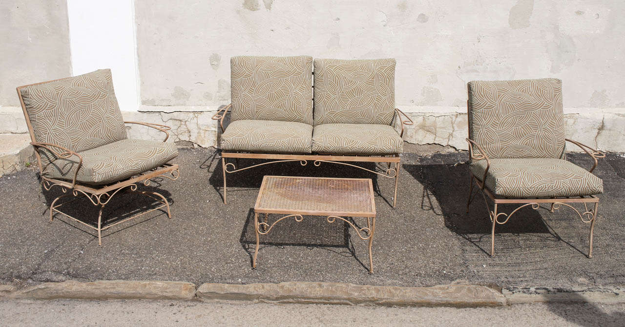 This nice vintage 60's Woodard 4 piece patio set includes a love seat and chair with a small cocktail table and jointed rocker. The set is painted in an old tan color that may or may not be original. The paint has achieved a certain amount of fading