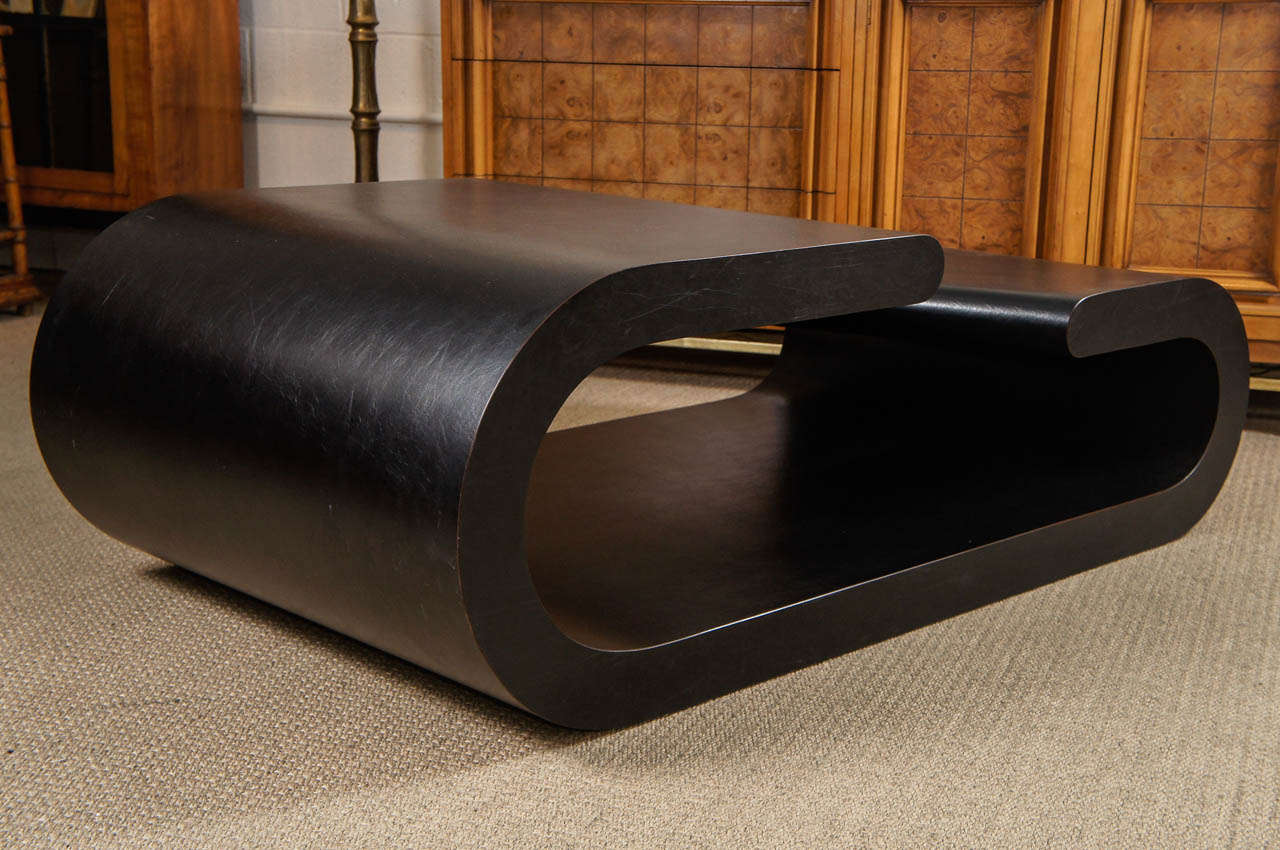 Here is a chic bi level coffee table with curved edges. The table is solid wood with a black vinyl laminate surface.