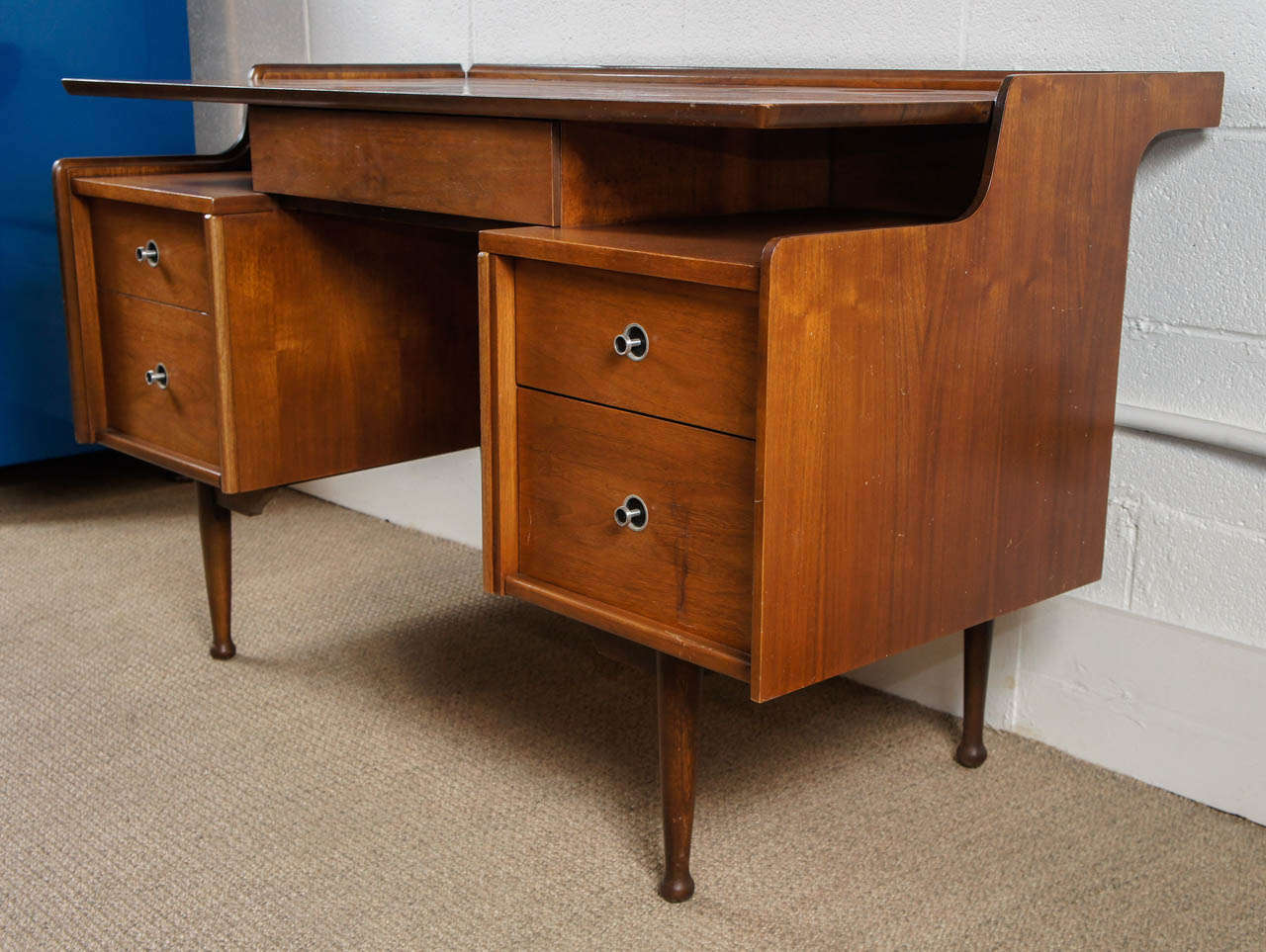 Here is a modern desk in a walnut finish by Hooker. This stylish small scale desk has a file drawer on the left and a raised platform top.