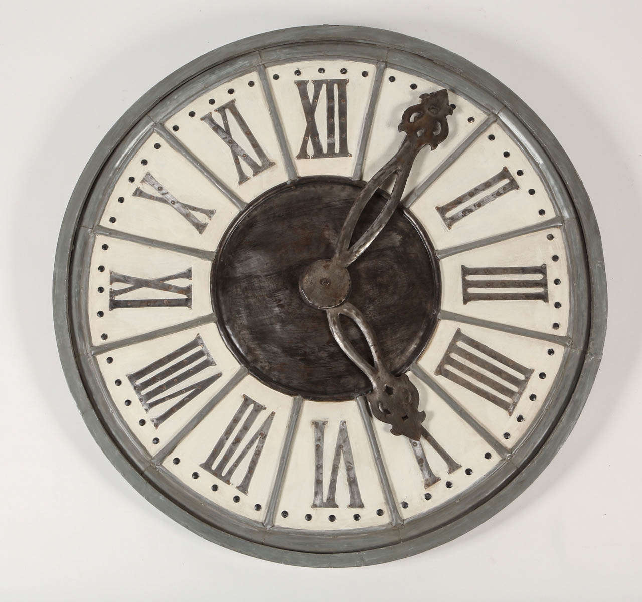 This large wall clock has a classic look with Roman numerals and large ornamental iron hands. It has an intentional patina which makes it feel like it came out of a grand old home. 
This would be a striking statement in a living room or an
