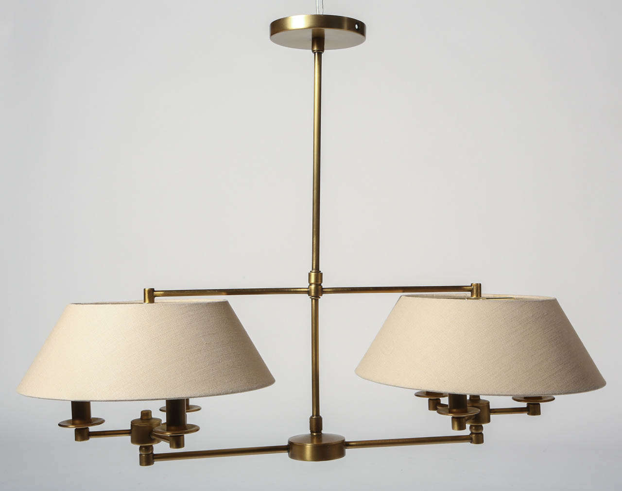 This handmade double arm pendant is a classically styled ceiling light fixture. Finished in antique burnished brass. Each shade conceals 3 bulbs making it a great task light. This light would be perfect over a kitchen island or a dining room table.