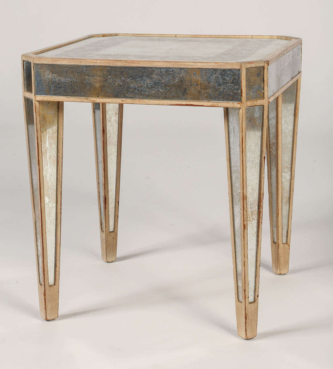 The glamour of the 1940's meet the simple silhouette of the neoclassical style in this versatile occasional table. The square églomisé  top with a silvered ground is decorated with a painted grapes and leaf border and edged within a molding. The