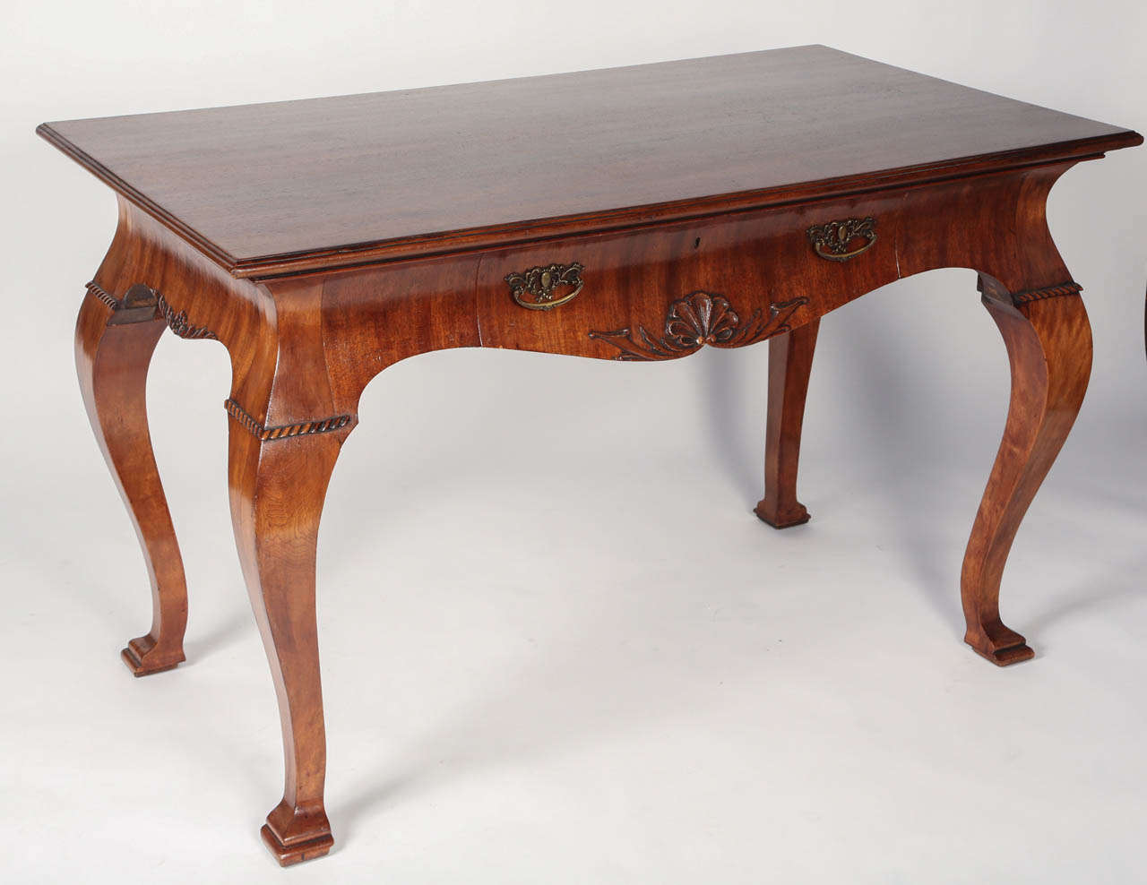 Beautiful mahogany desk in the George II style. The scalloped frieze is adorned with a shell motif and has one drawer. Cabriole legs terminate in square stepped feet.
This handsome desk would be the perfect piece in an office or a library.