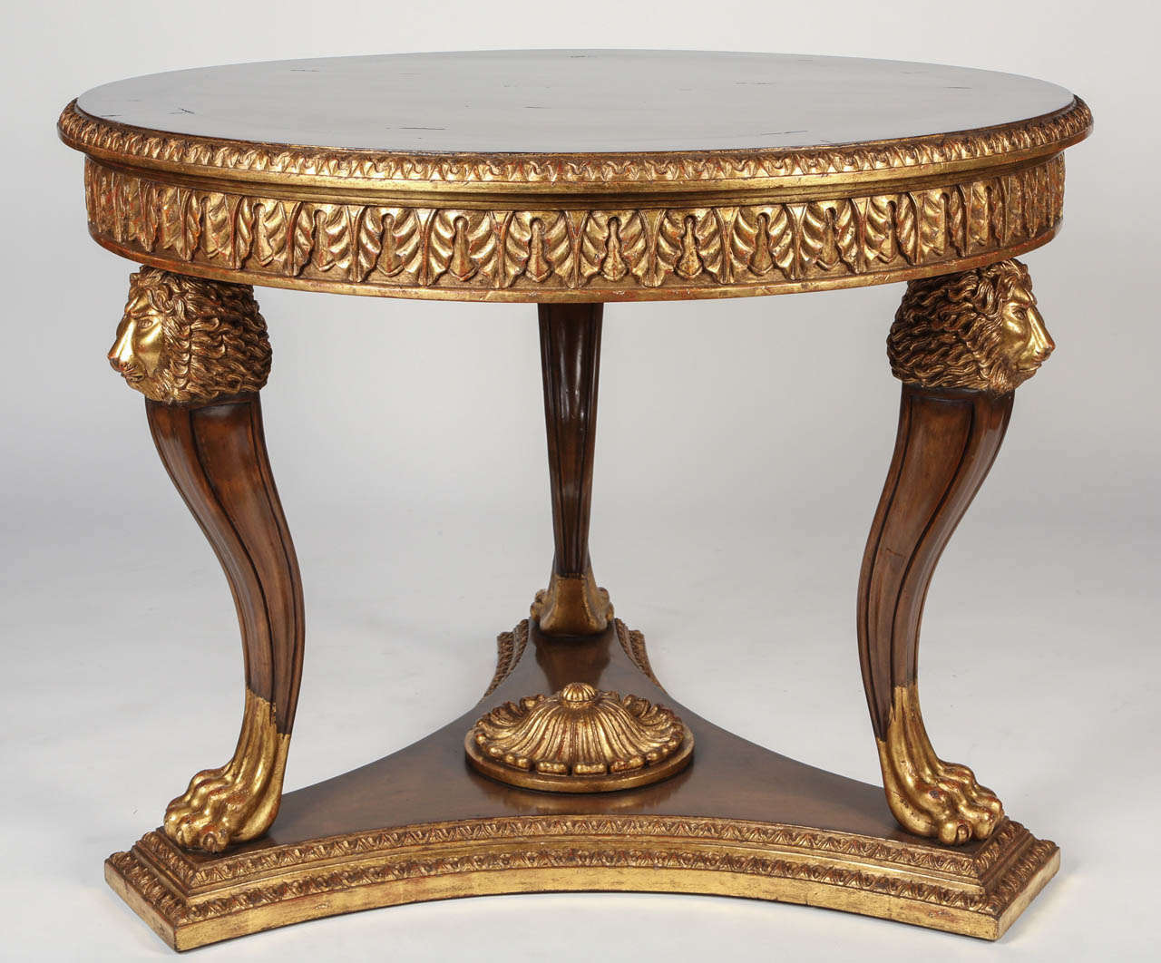 Trois pieds gracieusement incurvés avec une tête de lion et des pattes soutiennent cette table centrale en noyer délicatement sculptée.