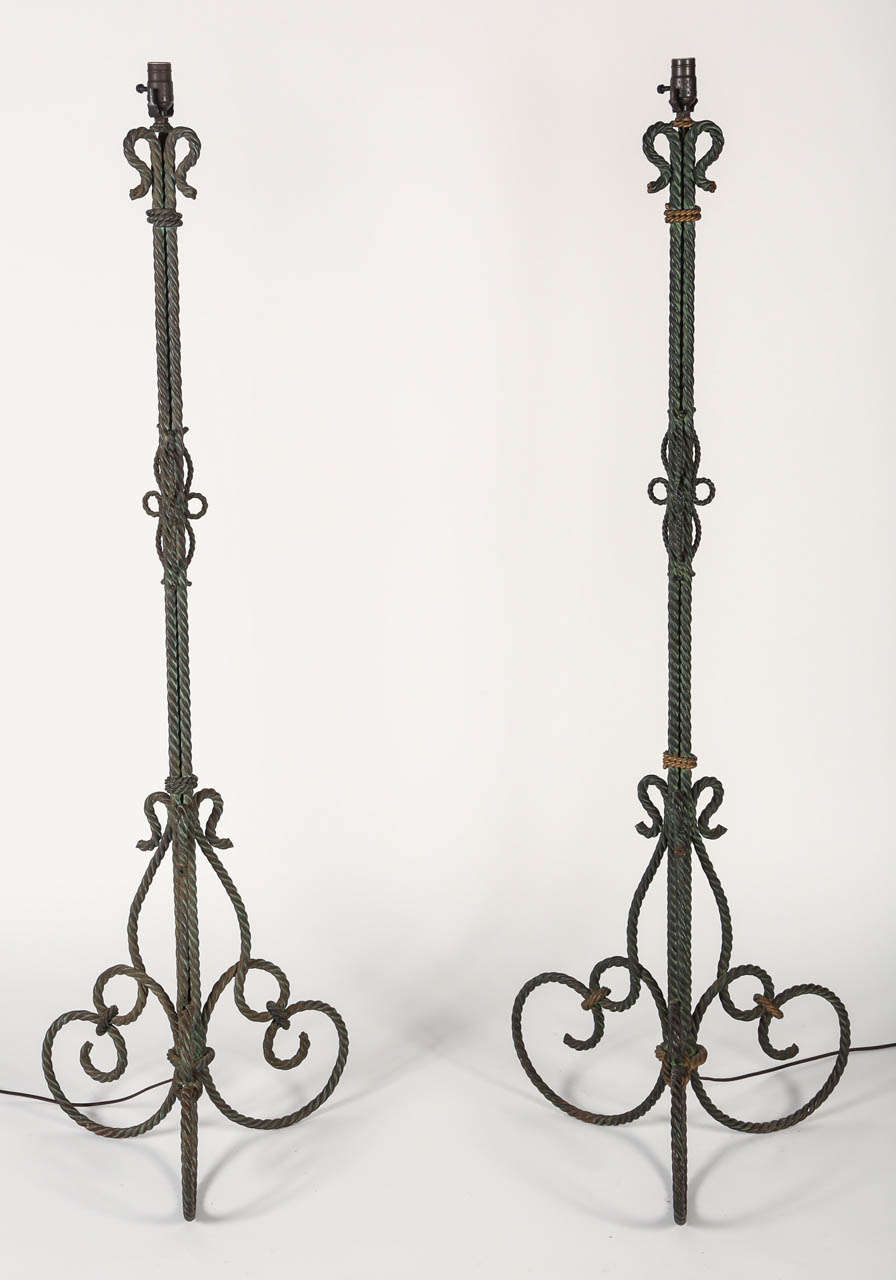 Rare pair of gilt-iron floor lamps with graceful curves of rope design. Beautiful details throughout.