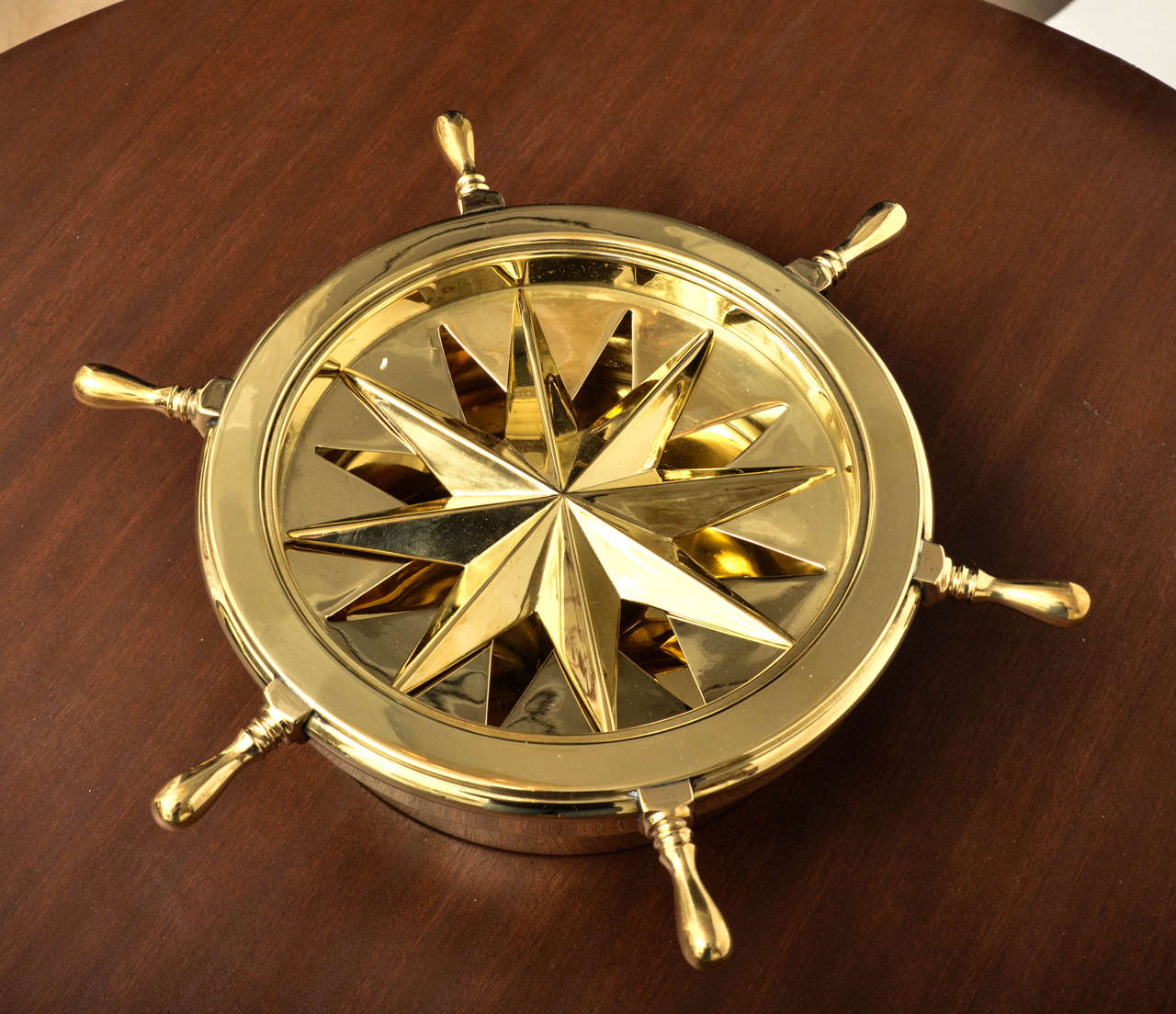 Nautical themed brass ash tray with rotating ship wheel cover and star form center.