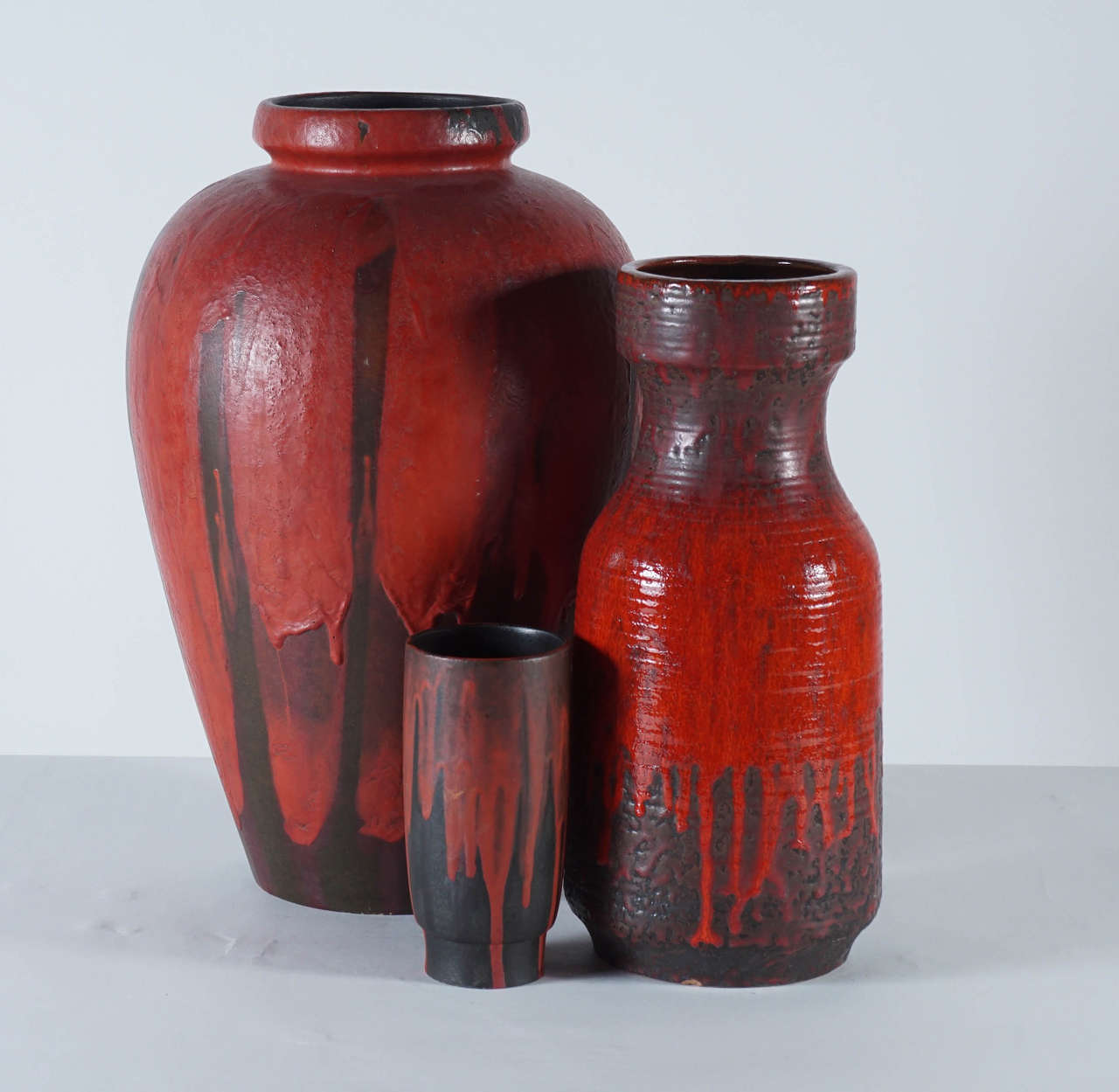 This collection is anchored by a monumental amphora in a dramatic glossy red and matte-black drip glaze. No cracks, chips, or repairs. Mint vintage condition. Medium vase: 5-1/2