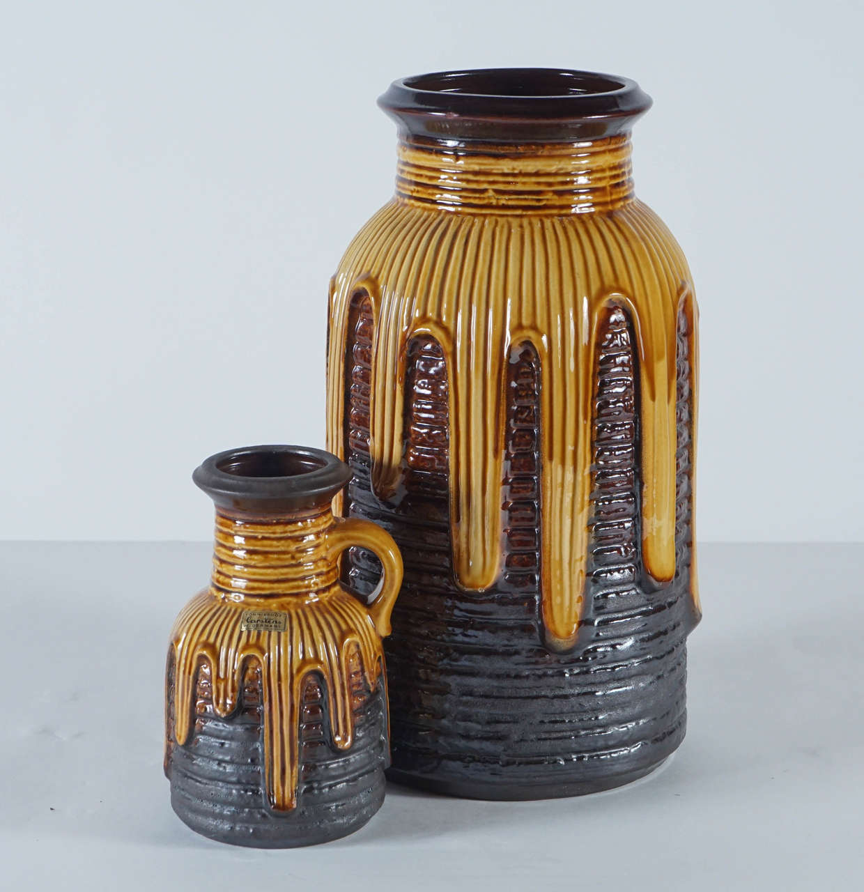 A pair of West German Pottery vessels in a rarely seen “honeypot” style. Honey yellow and chocolate glazes in haute-relief. No cracks or repairs. Mint vintage condition. Smaller ewer: 5 3/4