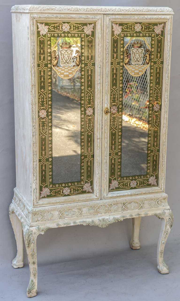 Cabinet, of carved wood, having a painted finish, its double cupboard doors inset with glass panels, hand painted with heraldic motifs, raised on cabriole legs. Paper tag reads:J.N. Slack and Company, Fifth Avenue, New York

Stock ID: D4497