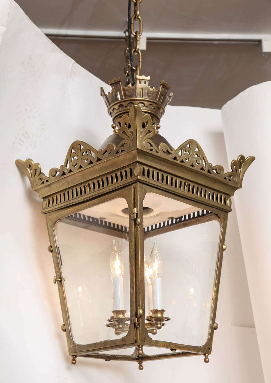 A square French bronze lantern with pierced fret gallery above 4 sections of glass and with hinged door, the interior fitted with 4 light cluster and having a white enamel ceilinged interior, the upper section with Atheneum motifs and having Corona