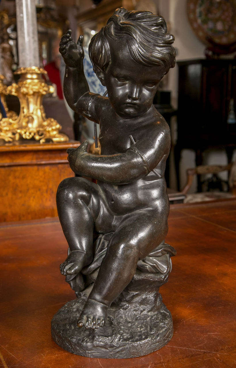 This is a working model of a  nude putto  with the signature  CLODION, on the base. Note the bronze pins  holding together the separately cast parts of the bronze.   The putto sits upon a  naturalistic   base. This bronze was either executed in the