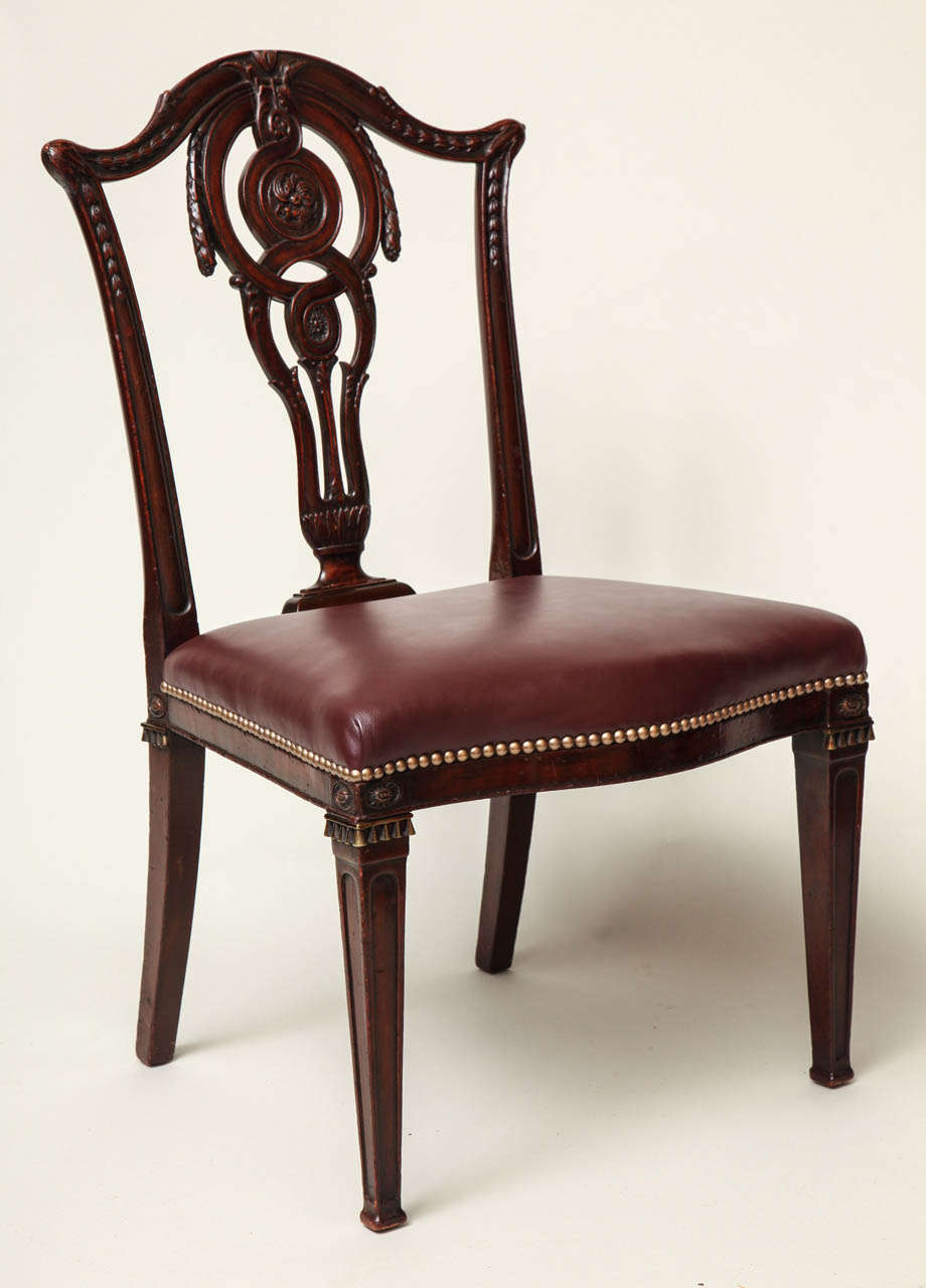 Very fine set of six English neoclassical dining chairs, the most unusual back splats with carved rosettes, honeysuckle and wreath carving, the crest rails with bellflowers, the legs with inset gilt bronze oval flower heads over square tapered legs