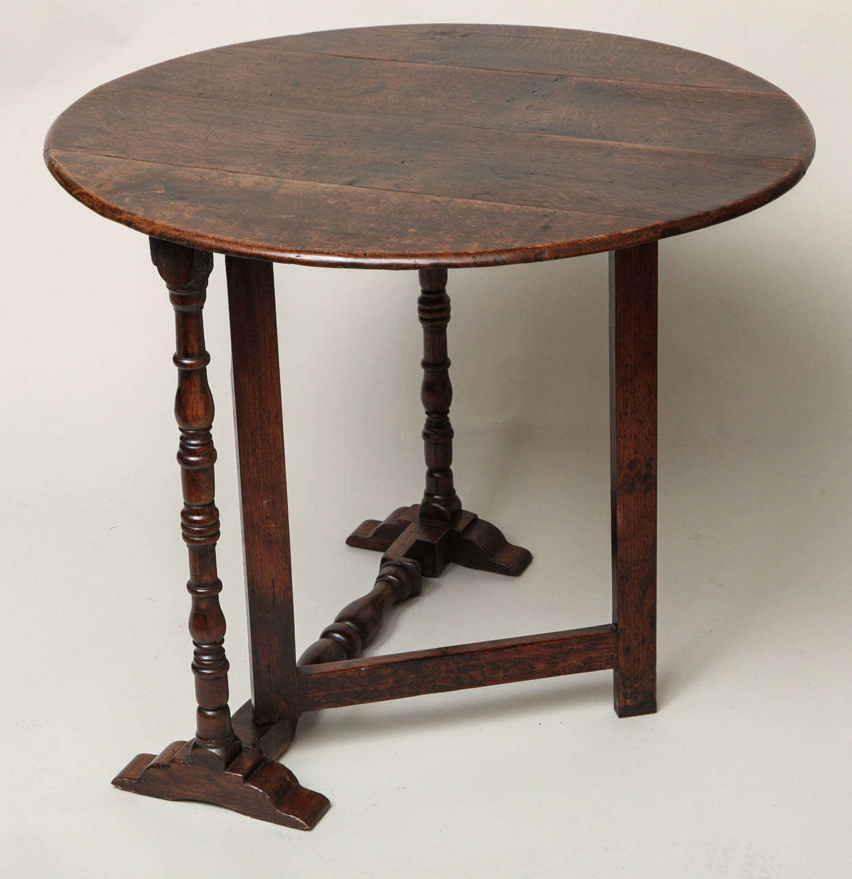 An unusual 19th century English coaching table in oak with a round top over turned and ringed legs having a swinging gateleg that fold flat for transportation and storage. A good looking and useful table.