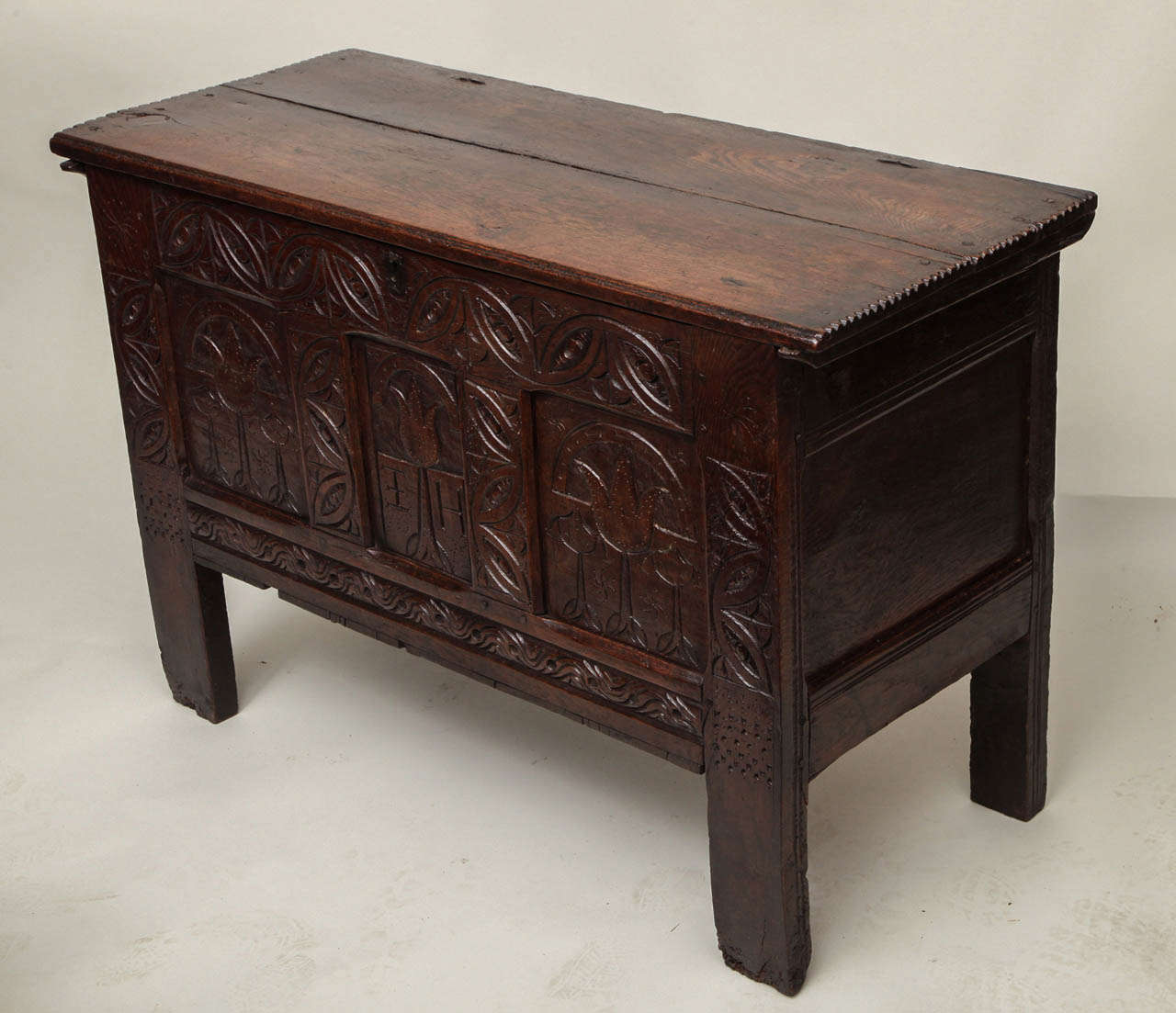 Fine early 17th Century English oak coffer, probably Dorset, circa 1630, the two plank lid with molded edge and original wire hinges, the paneled front with lunette carved stiles and rails, the three panels with arcaded tulips, the center with the