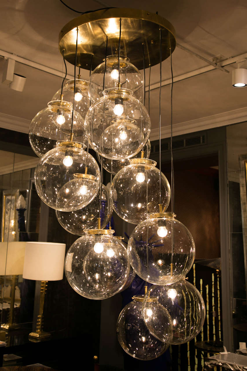 Pendant chandelier with 13 glass globes, brass support, adjustable to accommodate to different ceiling heights.