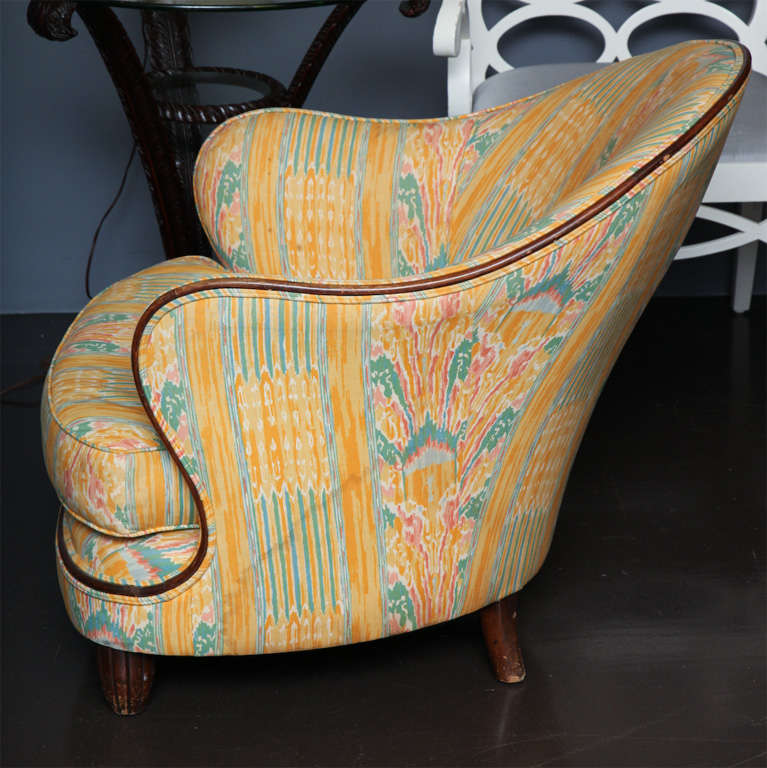 Art Deco style armchair upholstered in printed ikat with walnut trim and sculpted feet.
American, c. 1935.